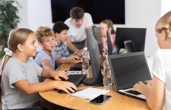 Concerned preteen girl and boy working together on computer in IT training room