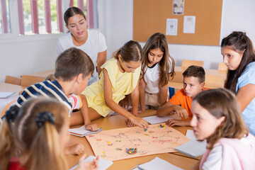 Teacher and group of kids playing board game in school after lessons. Children having fun playing...