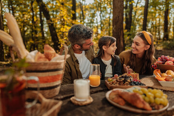 Mother, father and daughter laughing together during picnic in a forest