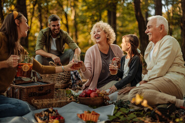 Whole Caucasian family having a picnic in the forest and drinking juice