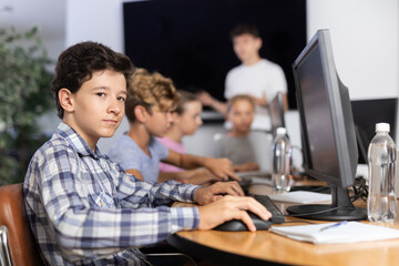 Concerned preteen boy working with computer programs with interest in training room