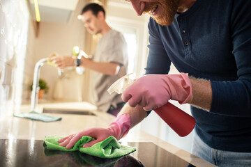 Young male gay couple cleaning their kitchen together