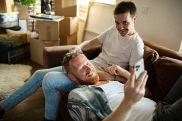 Young gay male couple relaxing on the couch after moving in their new apartment