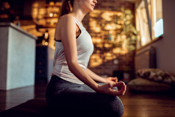 Young woman mediating in the living room of her home