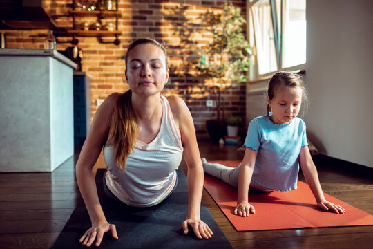 Young girl doing yoga with her mother in the living room at home