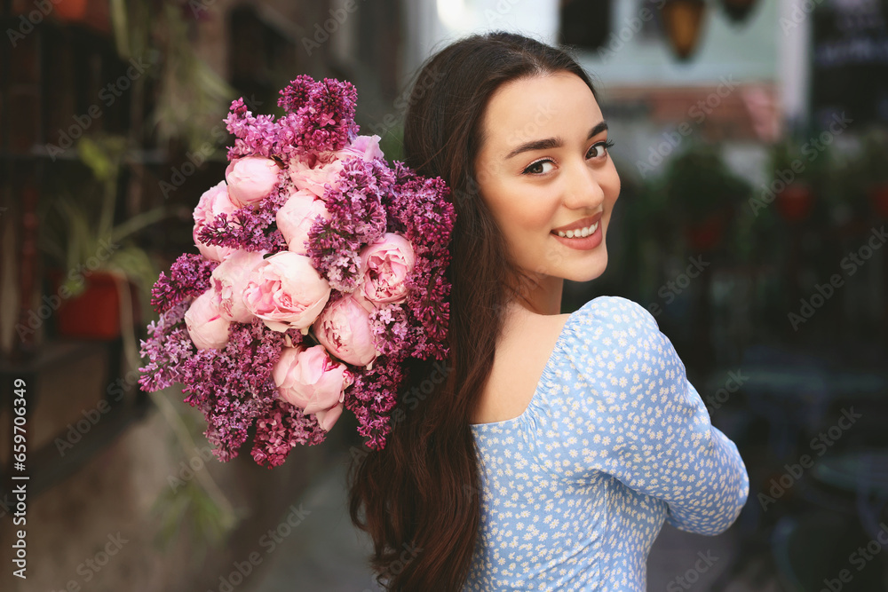 Poster Beautiful woman with bouquet of spring flowers outdoors