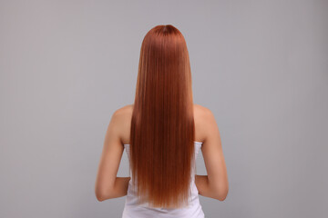 Woman with healthy hair after treatment on light grey background, back view