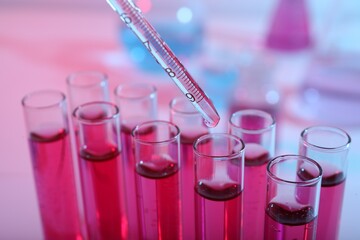 Dripping reagent into test tube with red liquid, closeup. Laboratory analysis