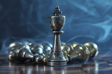 Fototapeta na wymiar King among fallen chess pieces on checkerboard against dark background, closeup