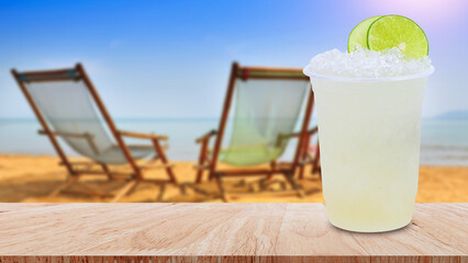 Cool freshly made lemonade in a plastic cups with crushed ice and lemon slices on wooden table with beach landscape nature background