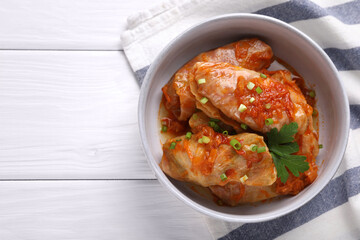 Delicious stuffed cabbage rolls cooked with homemade tomato sauce on white wooden table, top view. Space for text