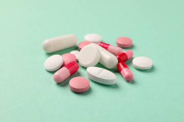 Pile of different pills on green background, selective focus