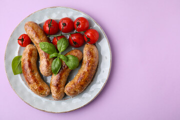 Plate with tasty homemade sausages, basil leaves and tomatoes on violet table, top view. Space for text