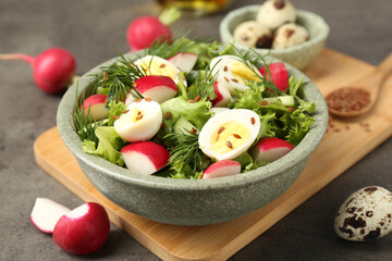 Delicious salad with radish, lettuce and boiled quail eggs on grey table, closeup