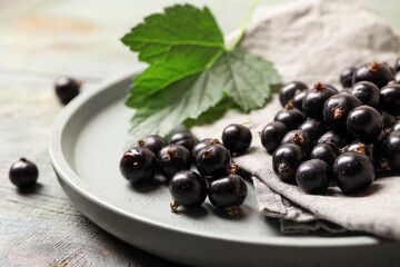 Ripe blackcurrants, leaf, napkin and plate on table, closeup