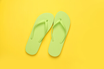 Stylish light green flip flops on yellow background, top view