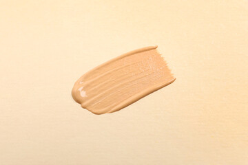 Smear of skin foundation on beige background, top view