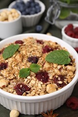 Tasty baked oatmeal with berries and nuts on wooden table, closeup