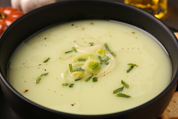 Bowl of tasty leek soup on table, closeup