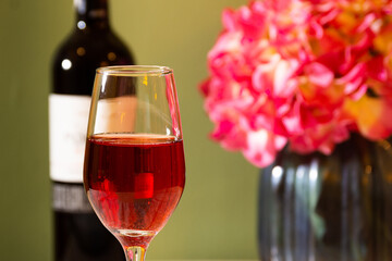 red wine and bottle with flowers in a green background
