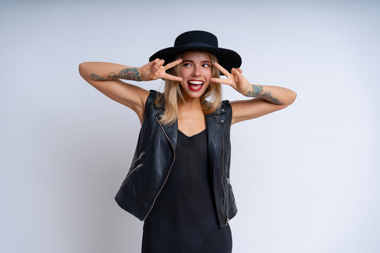 On a white backdrop, a pretty lady sports a black grunge look with lively makeup and a happy demeanor while striking poses. Emotional pretty face