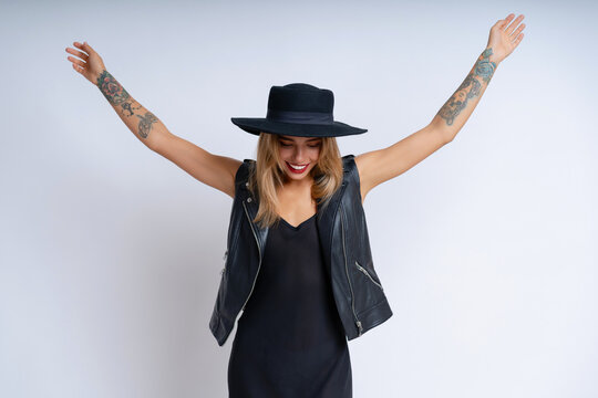A lovely woman in a black grunge outfit poses against a white background, wearing vibrant makeup and a cheerful expression
