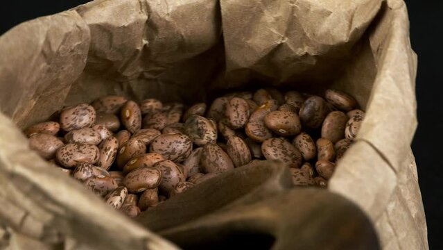 Spotted dry Pinto Beans in paper bag rotate in close-up macro view