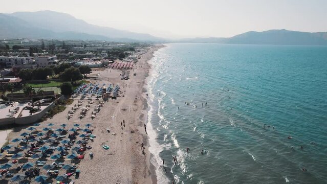 Aerial view of a sandy beach full of sunbeds and the Aegan sea, Crete, Greece. High quality 4k footage