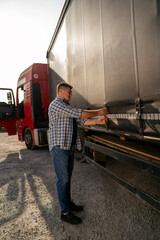 Truck driver securing his cargo, checking trailer 