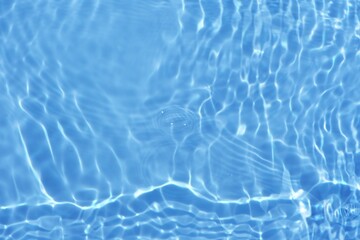 Defocus blurred transparent blue colored clear calm water surface texture with splashes reflection. Trendy abstract nature background. Water waves in sunlight with copy space. Blue watercolor shine.