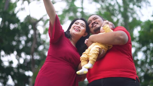 Happy young indonesian family with father, son, and mother pointing