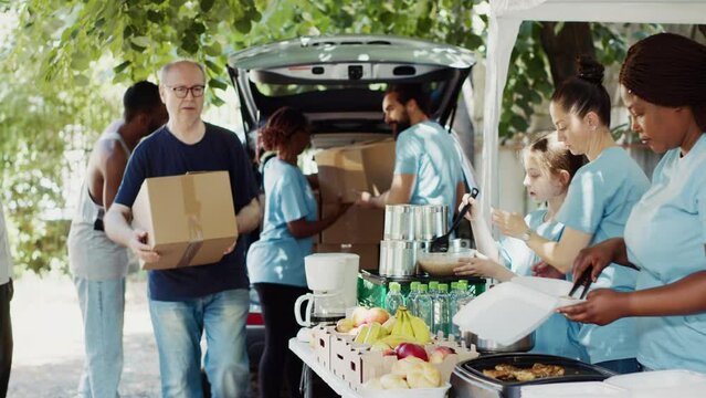 Group of volunteers handing out packed food to needy such as the elderly and homeless people. The sincere gesture of kindness makes the less fortunate individuals happy and relieves their suffering.