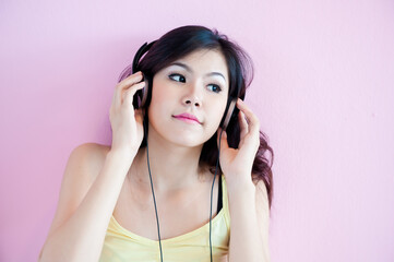 A young, attractive Asian woman is happily listening to music.
