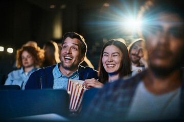 Young mixed couple watching a comedy in the movie theater