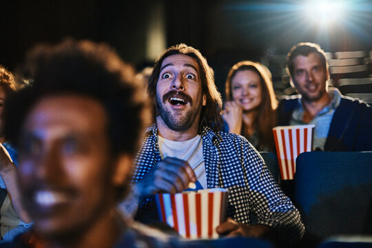 Young Caucasian man watching a scary movie alone in the movie theater