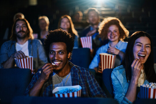 Young and diverse group of friends watching a movie in the movie theater
