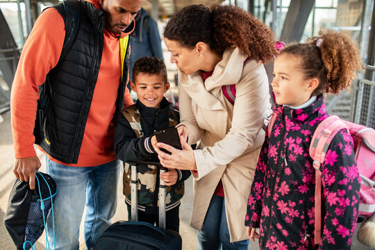 Young mixed family using a smartphone for train routes at the train station