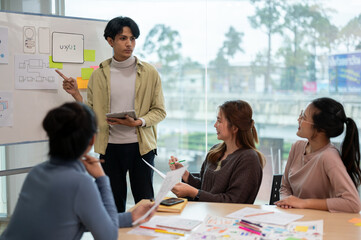 Young smart UX UI designer presenting his idea to the team, presentation during the team meeting.