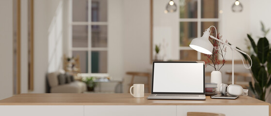 A white-screen laptop mockup and accessories on a table in a modern, cosy living room.