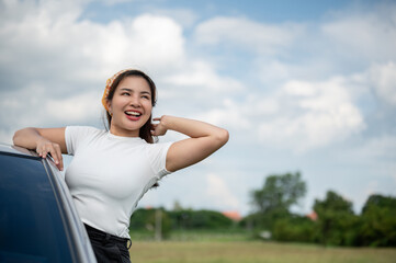 A happy woman feeling fresh, enjoying the wind outside the car and having fun during her road trip.