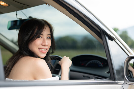 A beautiful and attractive Asian woman is driving a car and traveling around the countryside.