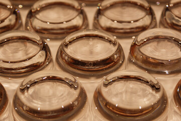 照明を反射してキラキラ反射する並べられた空のたくさんのグラスの底、パーティー・お祝い・レストラン