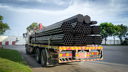 Trucks with long trailers carrying steel bars for building construction. Construction steel is ready to be delivered to the customer.