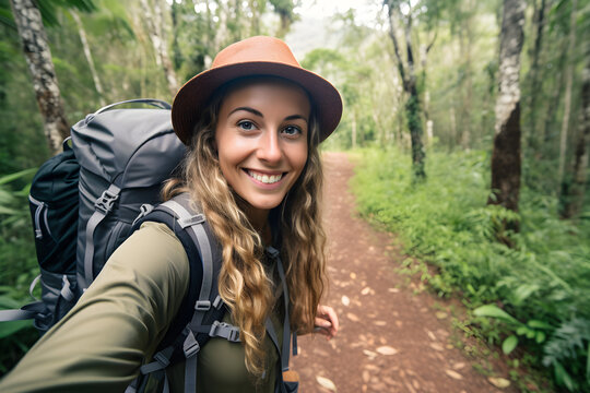 Happy traveller woman with backpack taking selfie picture in jungle - Travel blogger taking self portrait with smart mobile phone device outside - Life style and technology concept