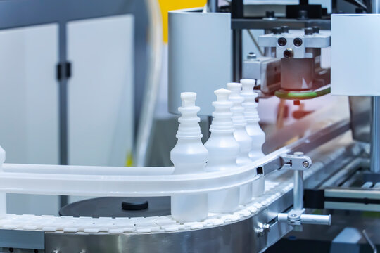 Moving polypropylene white bottles on conveyor belt of automatic liquid filling machine