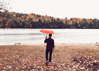 man walking with red umbrella in the fall