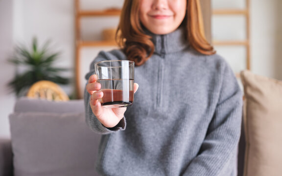 Closeup image of a young woman holding and serving a glass of water