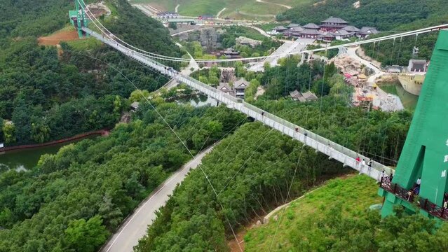 Stunning aerial view of suspension glass bridge at Huaxiacheng theme park in Weihai, China