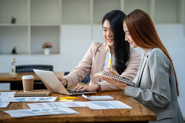 Two Asian businesswomen working together on digital tablet Female executive meeting and having a creative discussion in office using tablet PC and smiling