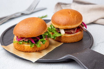 hot burgers with lettuce and vegetables on a wooden board